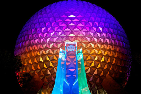 Spaceship Earth at EPCOT lit up at night with the fountain in the foreground